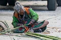 An elderly woman splitting bamboo.