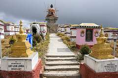 Mandala Top, a sacred Buddhist pilgrimage site featuring 108 stupas, known as Manes, arranged in concentric circles around a golden Buddha statue.
