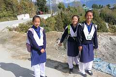 Three school girls in their uniforms on the road in the upper town of Tawang.