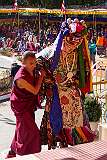 A masked dancer at the Drub-chod-Chen-Mo Torgya returns up the steps to the main hall of the monastery accompanied by a monk.
