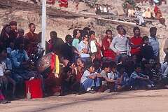 A man playing the “Dhyangro” drum between the crowd watching the Tibetan Opera.
