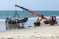 A crane lifting a fishing boat onto the shore, on Chappakkadavu Beach, Kodamthuruth, between Kochi and Alappuzha.