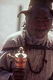 An elderly man with a mani wheel (mani-chos-'khor), a Buddhist prayer wheel.