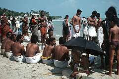 A “puja”, a Hindu ceremony requested by the seated men, starting on the beach in Rameswaram.