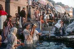 Women bathing and pouring water, a ritual in the Ganges river in Varanasi.