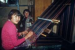 Yangdzon, weaving a carpet, with Yishey Wangmo watching.