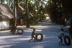 Children playing with tyres in a village street on Betio.